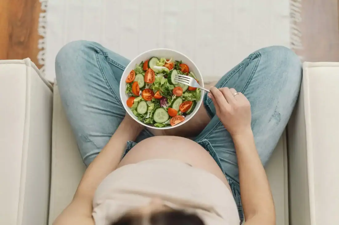 Healthy salad with vegetables and a pregnant woman eats healthy food.